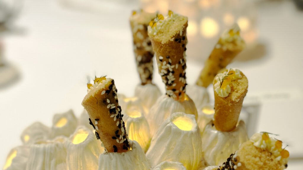 Knusprige Mini-Cornets mit Sesam, Creme und Kaviar elegant serviert auf einer leuchtenden Keramikskulptur